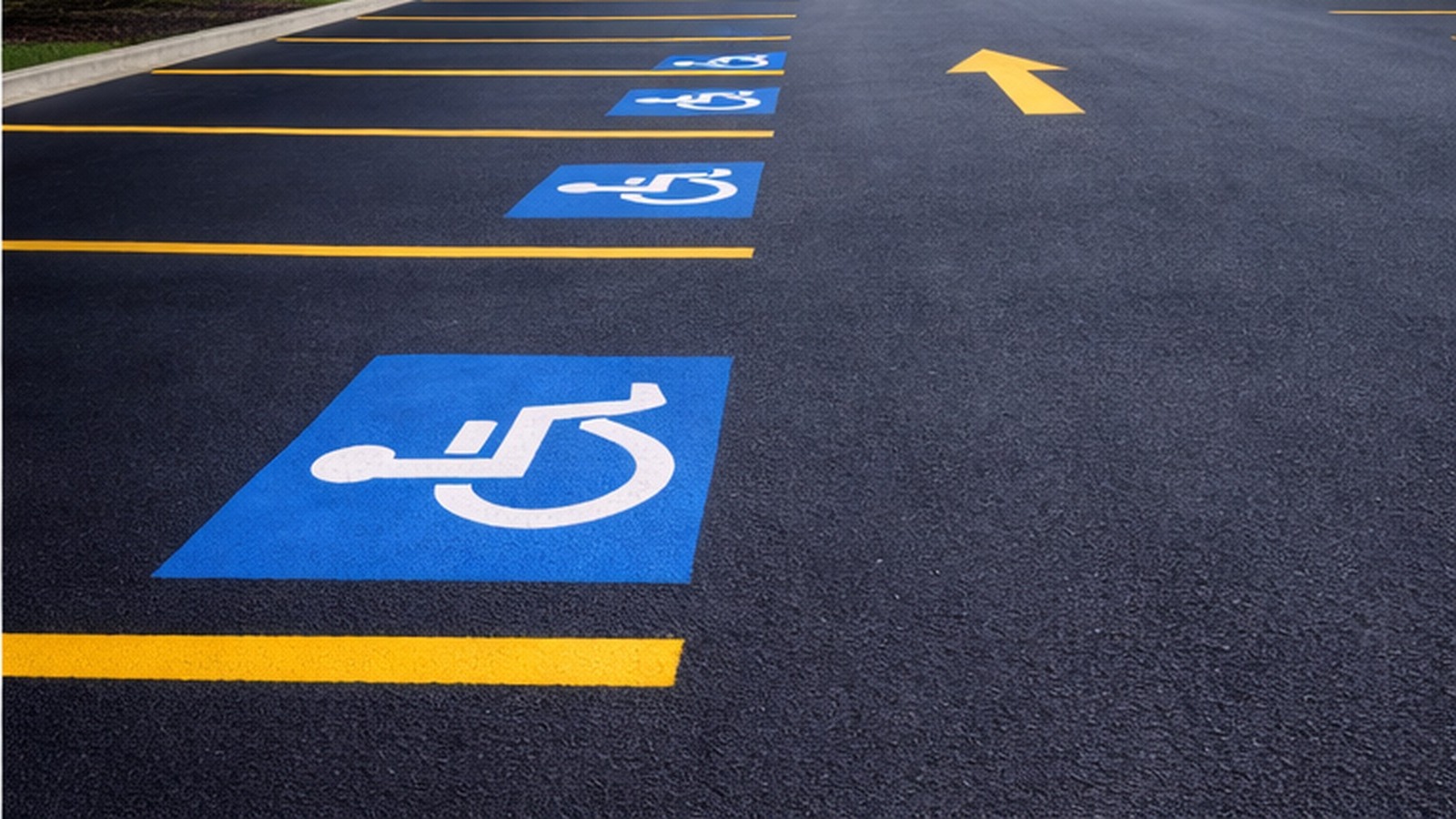 Freshly painted parking lot striping with handicap spaces and a directional arrow on dark asphalt